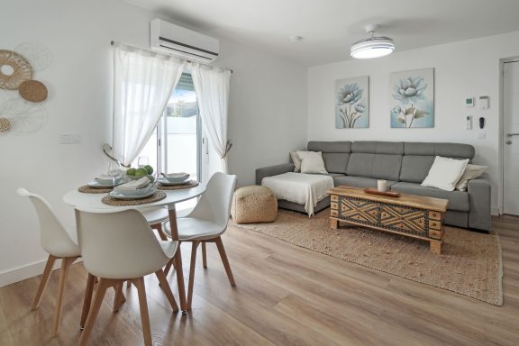 Salón moderno y luminoso con sofá, mesa de comedor y decoración minimalista.