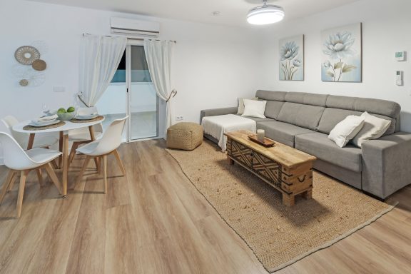 Sala de estar moderna con sofá, mesa de comedor y decoración minimalista. Suelo de madera.
