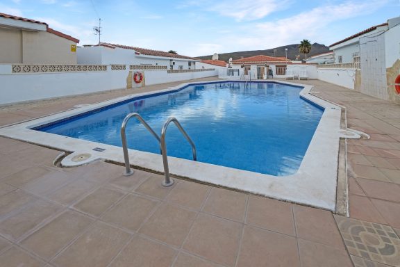 Piscina al aire libre con escaleras, rodeada de edificios y cielo despejado.