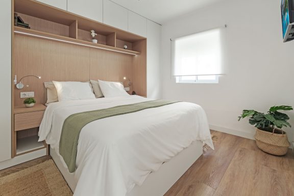 Dormitorio moderno con cama doble, paredes blancas y decoraciones minimalistas.
