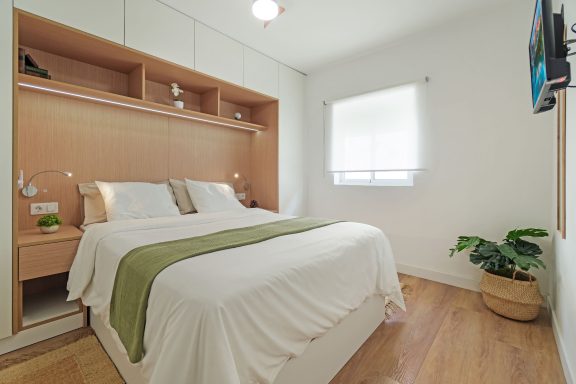 Habitación moderna con cama doble, decoración minimalista y planta en una maceta.