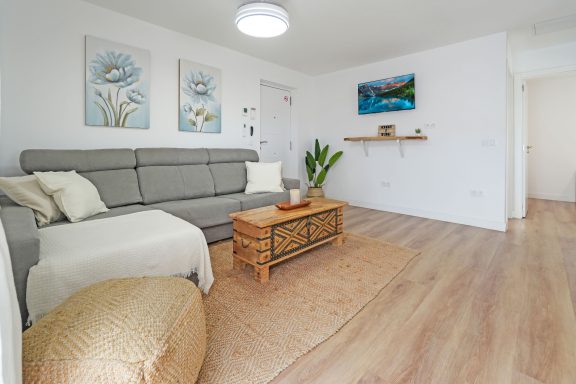 Sala moderna y luminosa con sofá, mesa de café y decoraciones en las paredes.