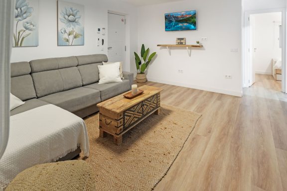 Sala de estar moderna con sofá gris, mesa de madera y decoración minimalista.